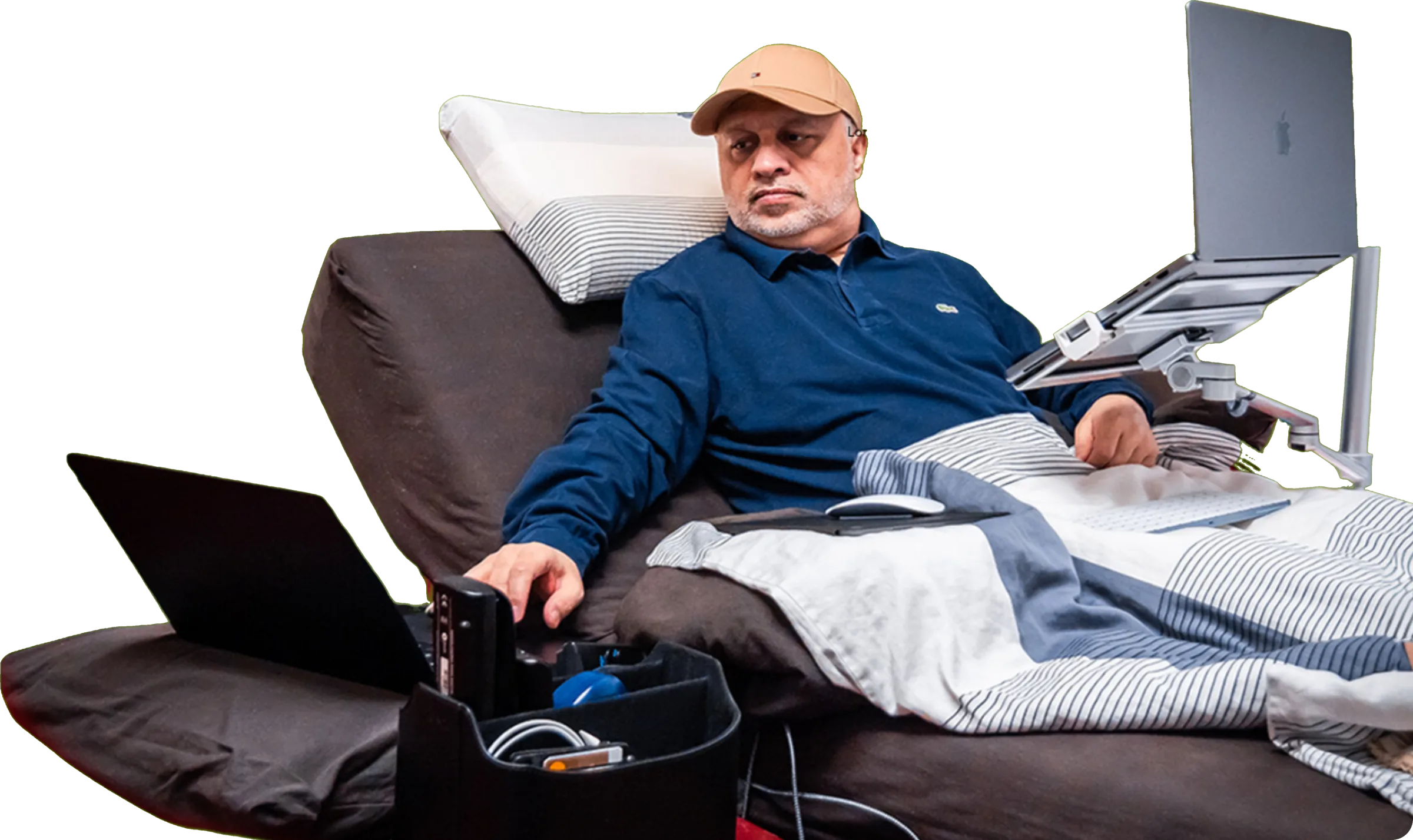 Nadeem Arif working from his bed, a laptop mounted on a stand in front of him
